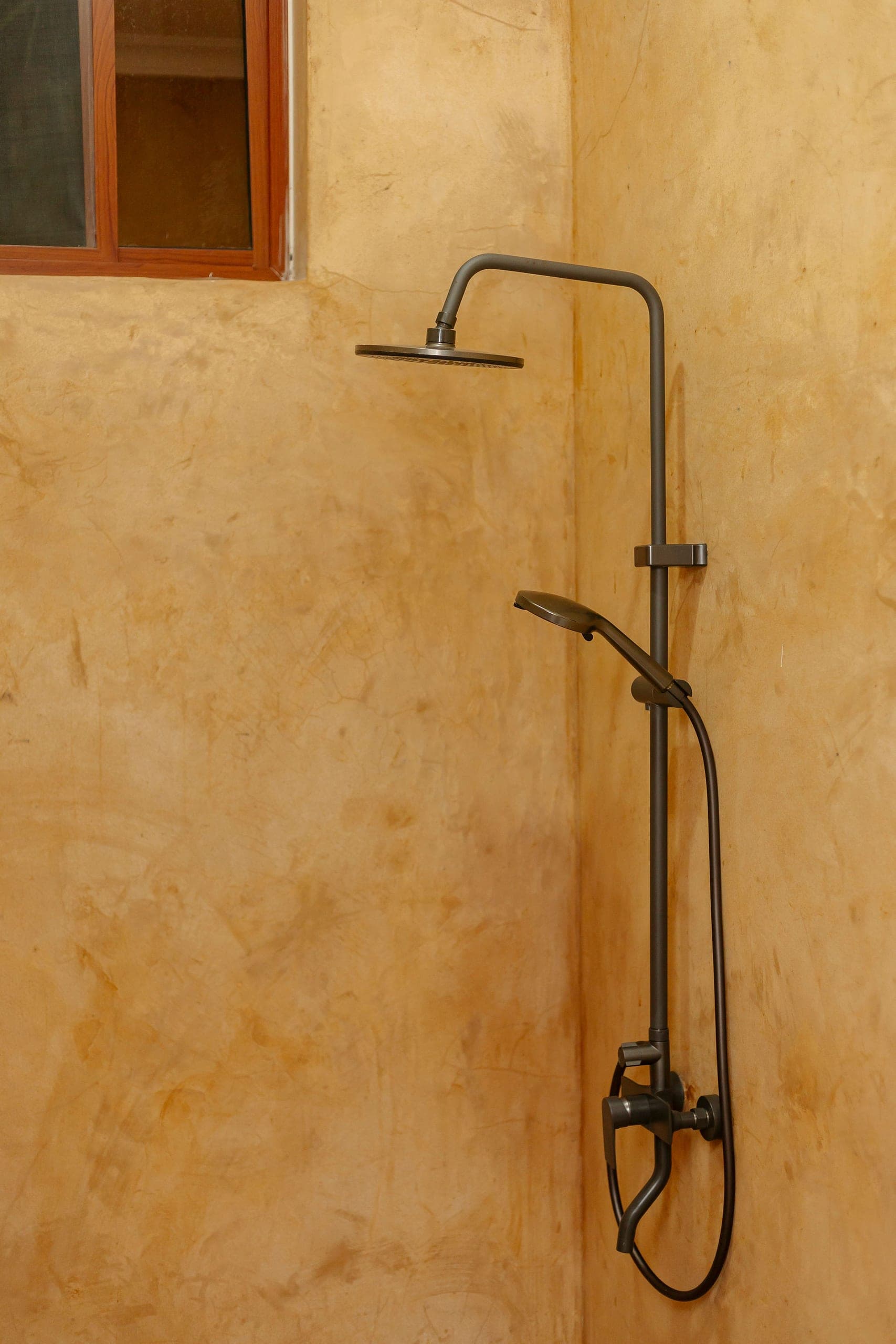 Rain shower head and handheld shower against warm plaster walls