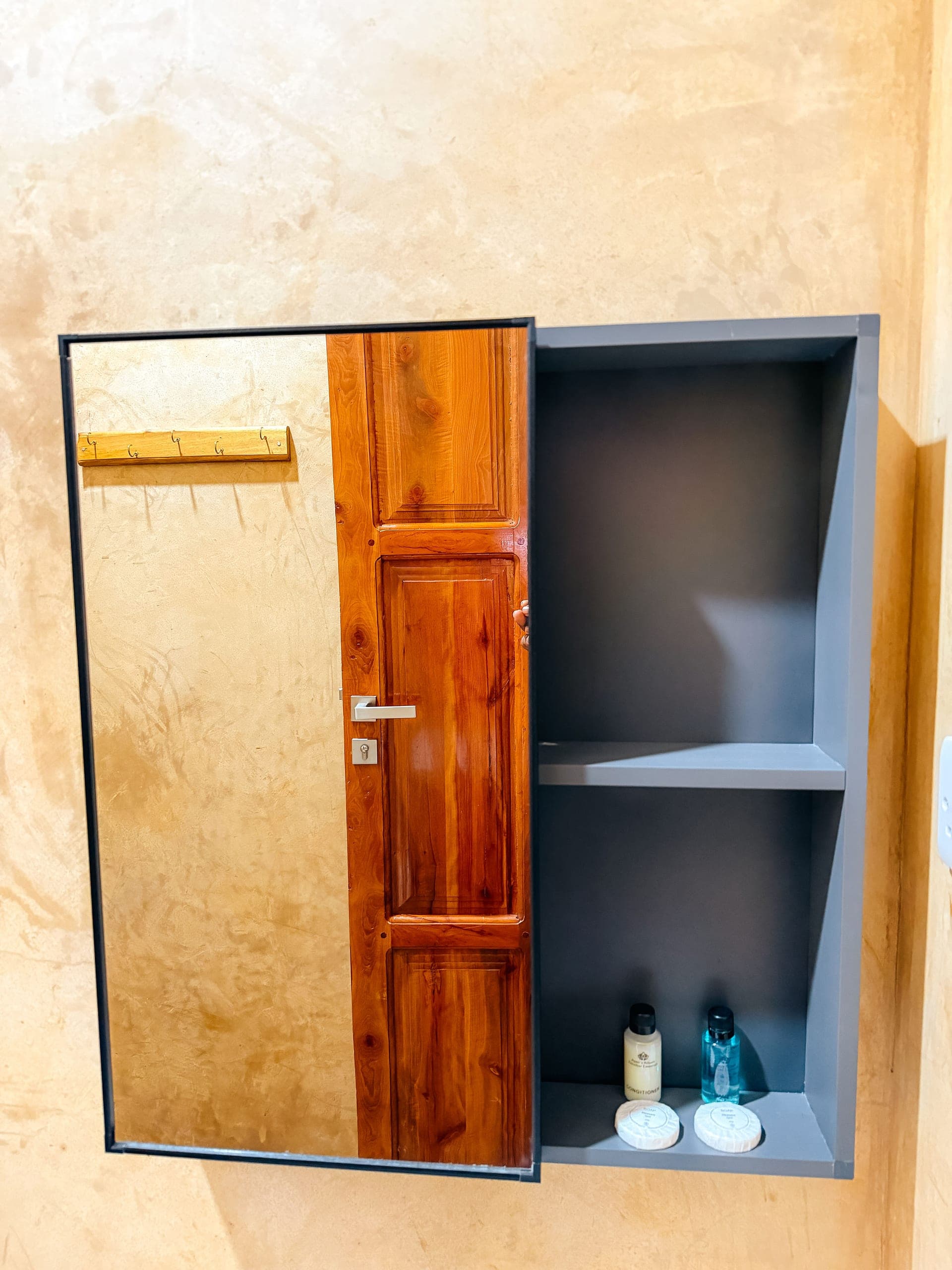 Mirrored bathroom cabinet stocked with shampoo, conditioner and soap