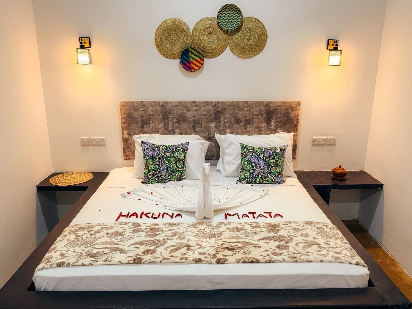 Guest room bed decorated with folded towels and flower petals