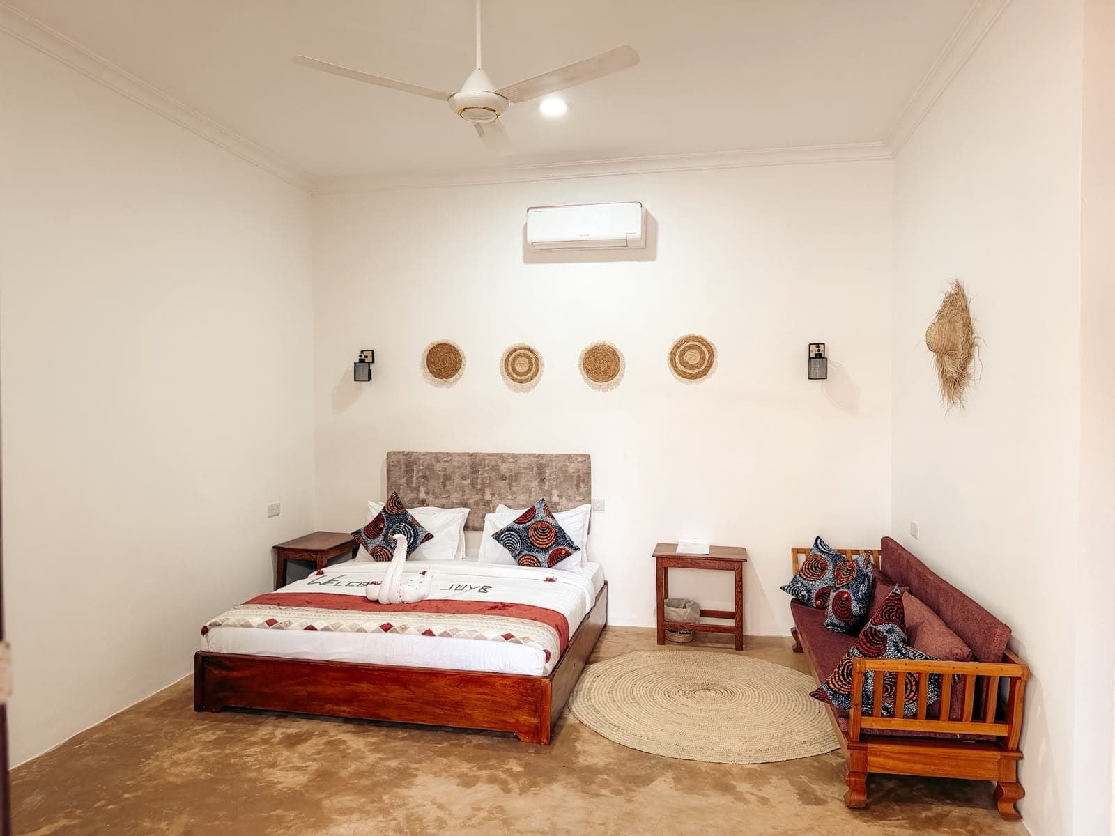 Bright deluxe room with a wide bed and woven wall decor