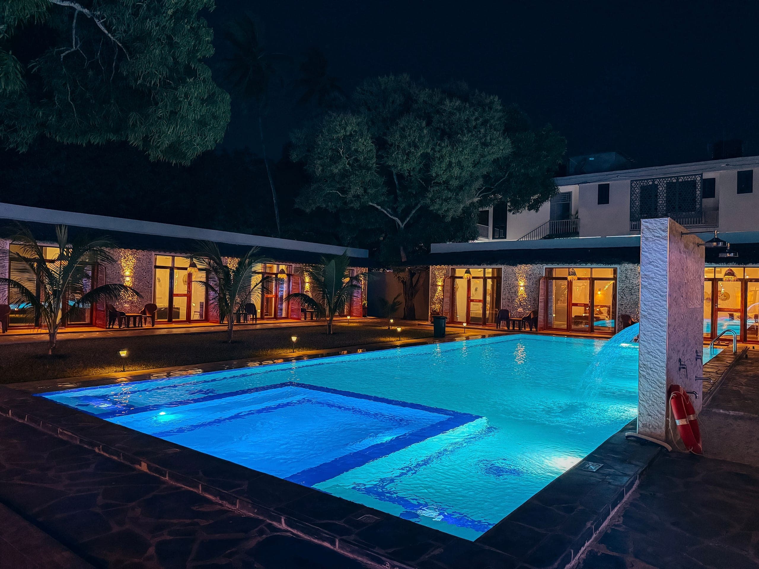 Wide view of the illuminated pool and resort rooms