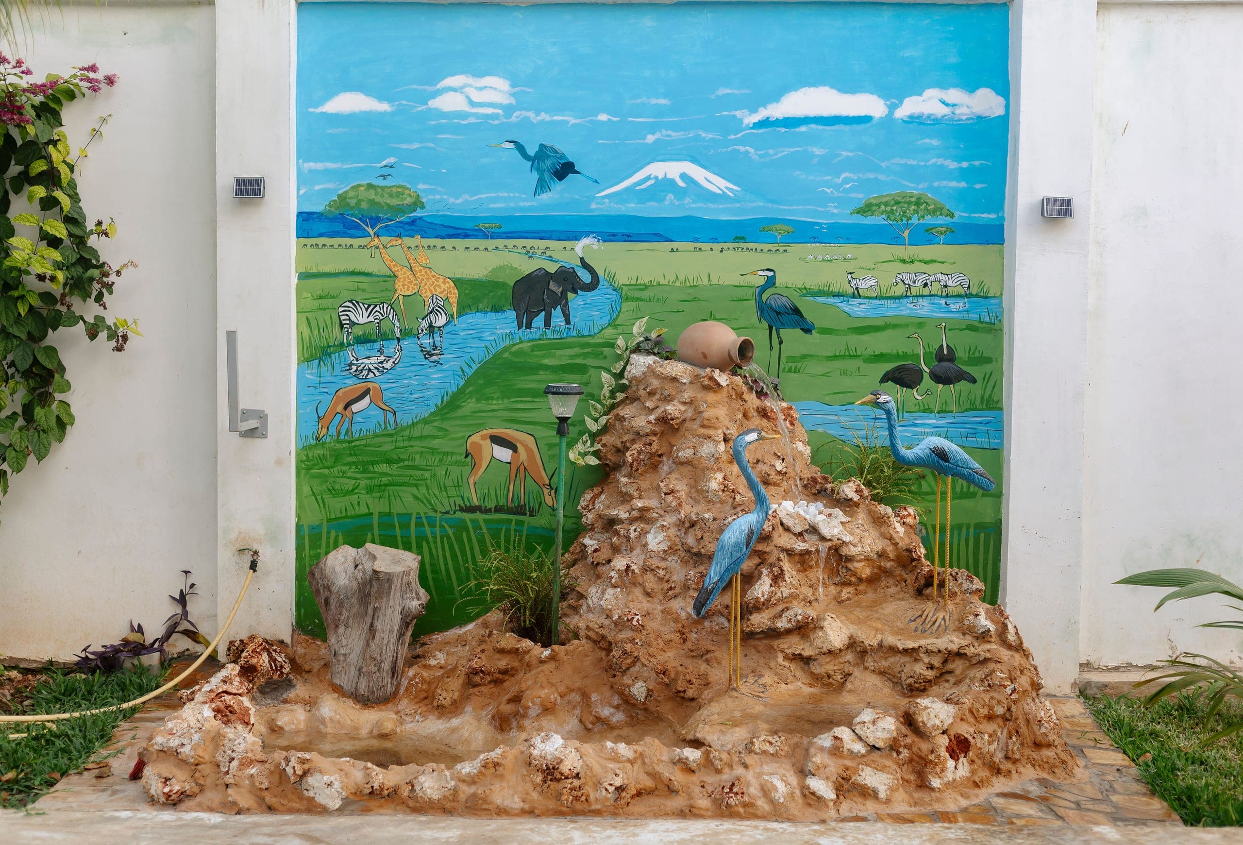 Hand painted safari mural behind a coral rock water feature