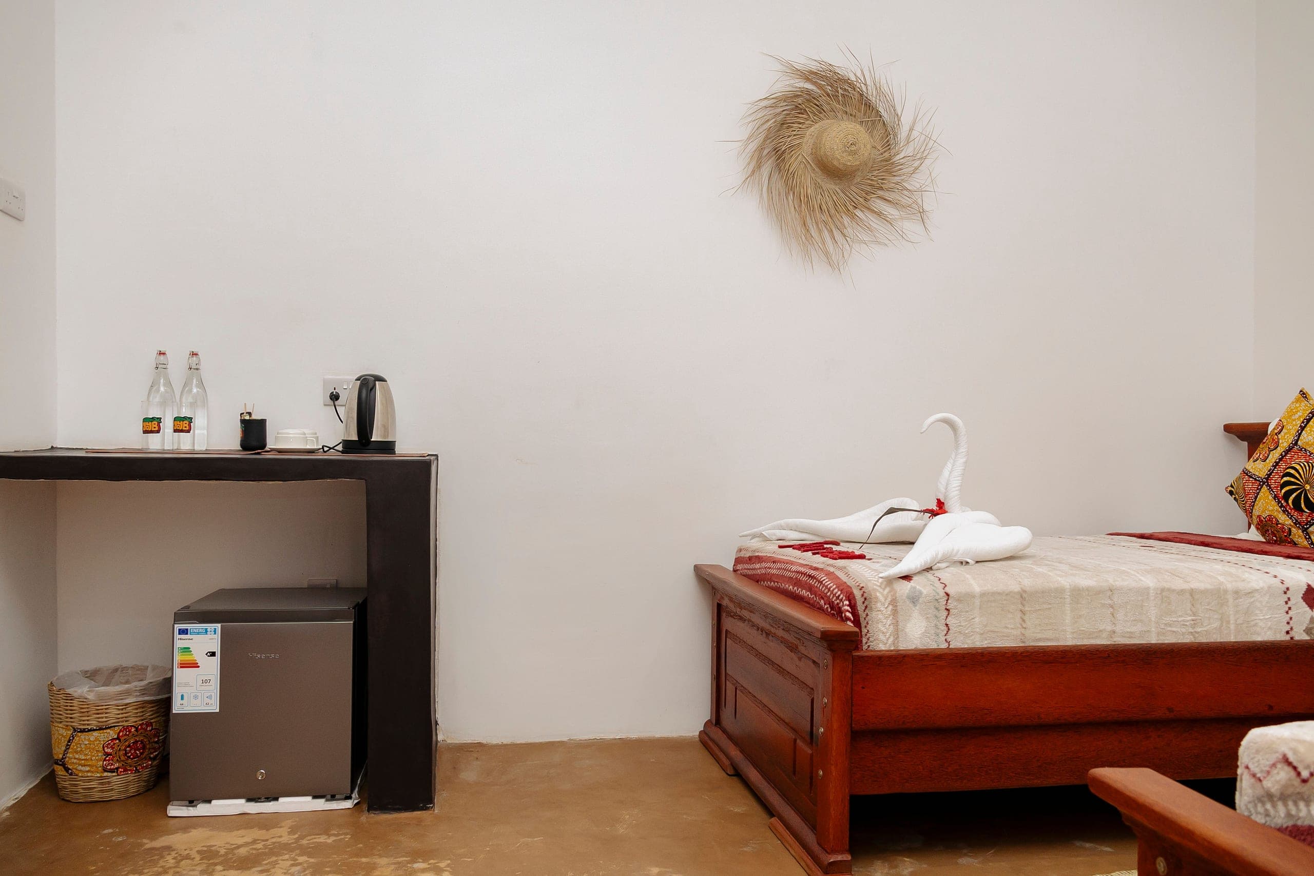 Corner of the twin room with a kettle, cups, bottled water and a mini fridge
