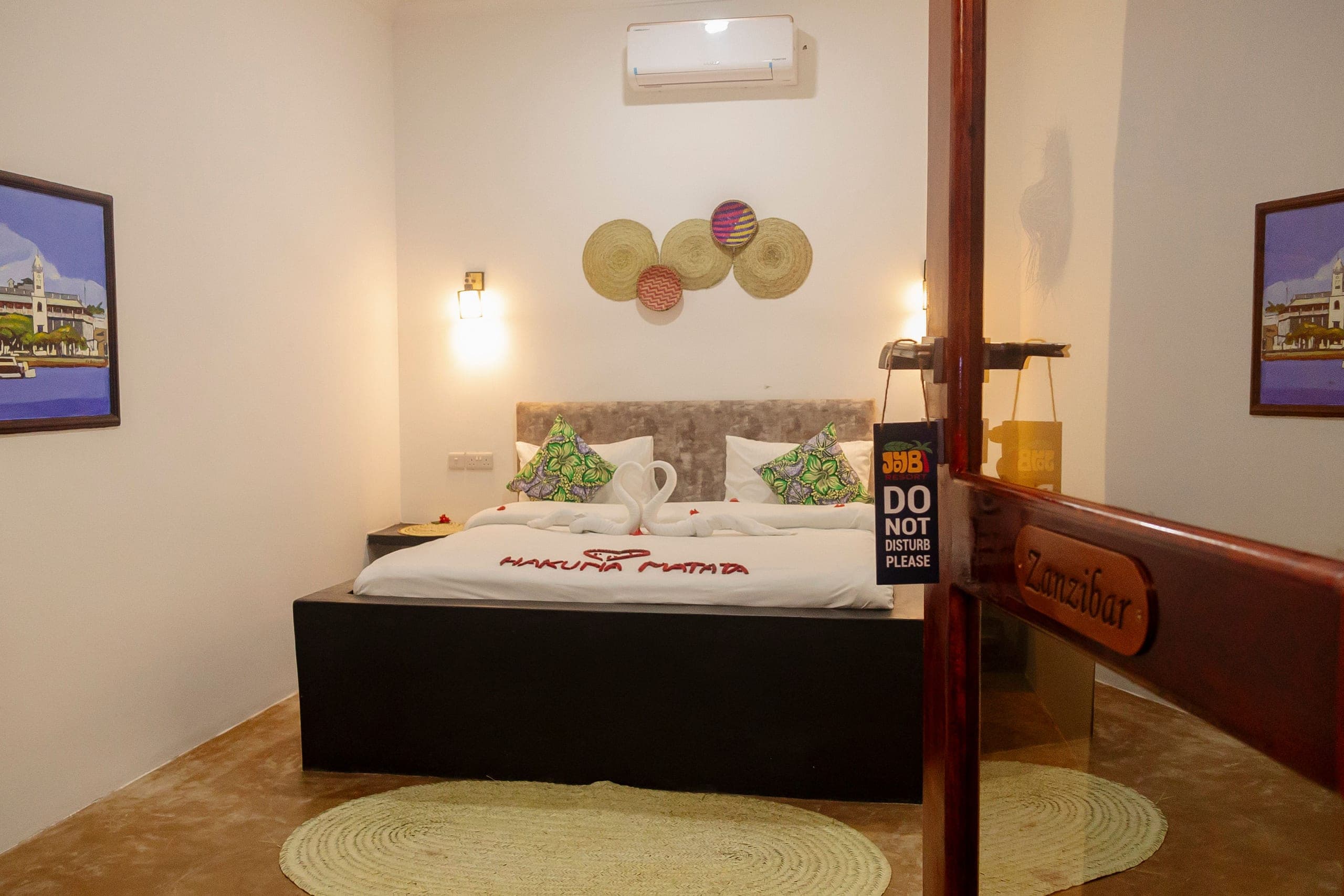 Interconnected room with a wide bed, petal welcome message and Stone Town paintings