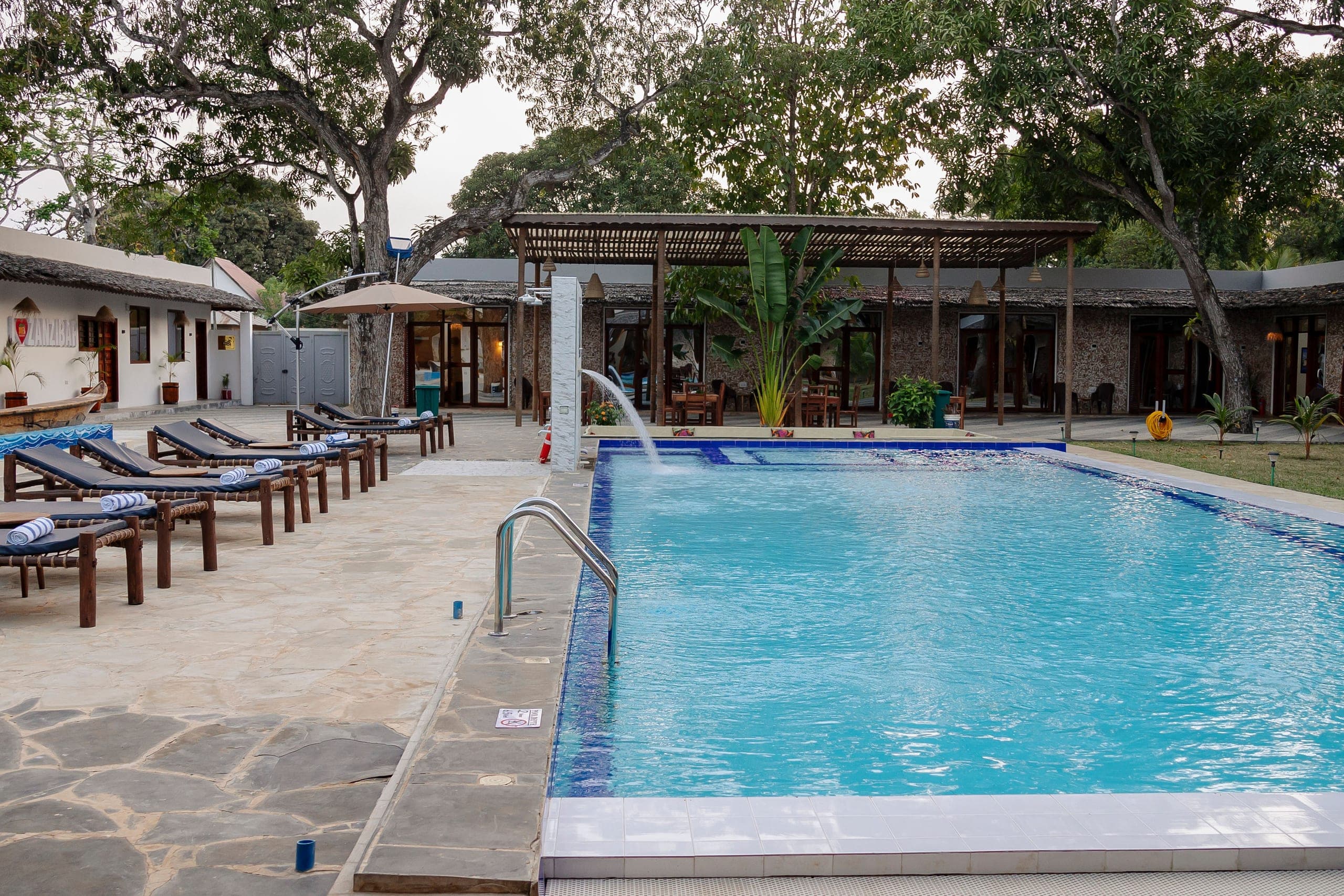 Loungers with rolled towels along the pool, waterfall running at the far end