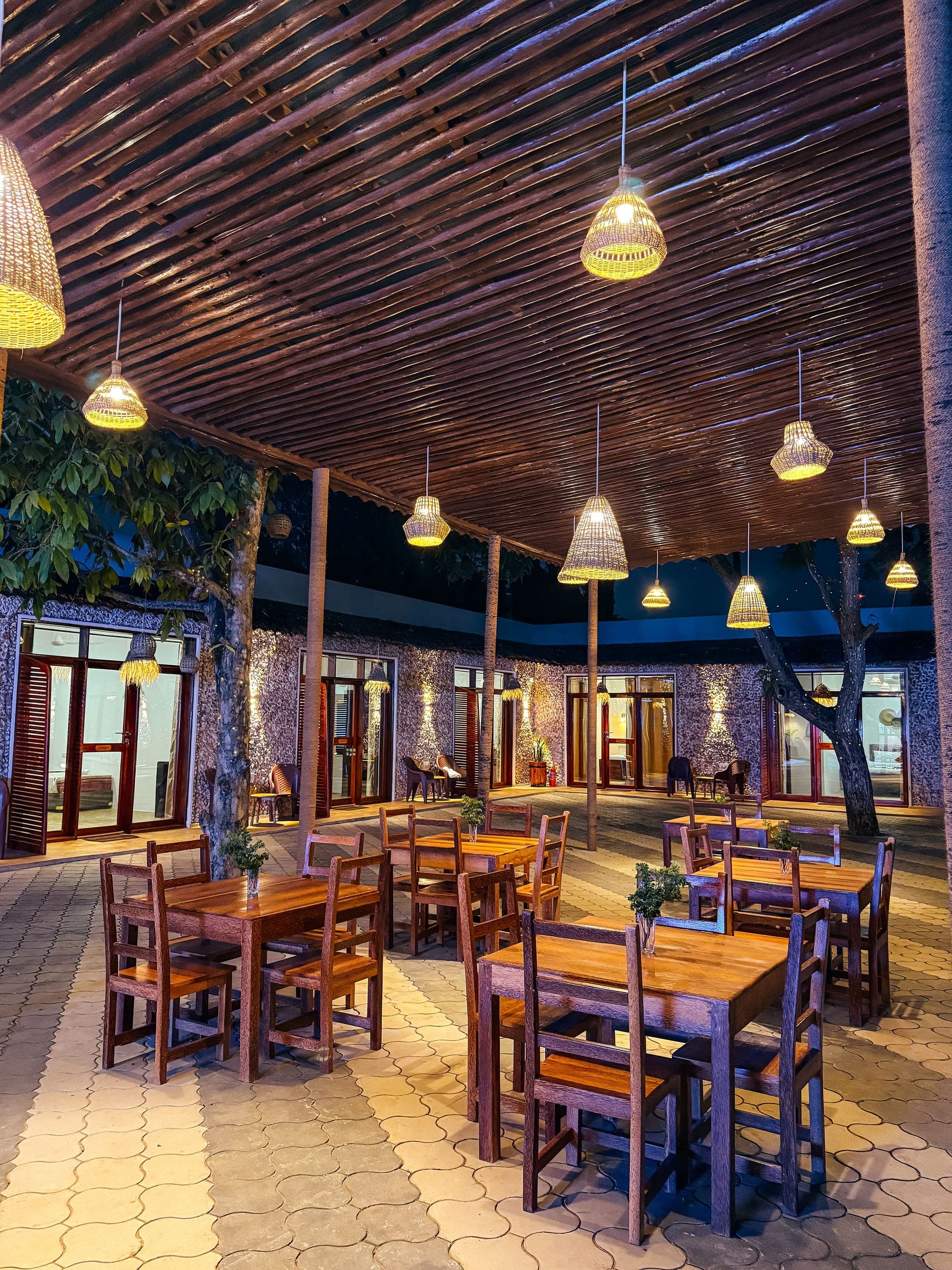 The open air restaurant at night, wicker pendant lights over wooden tables